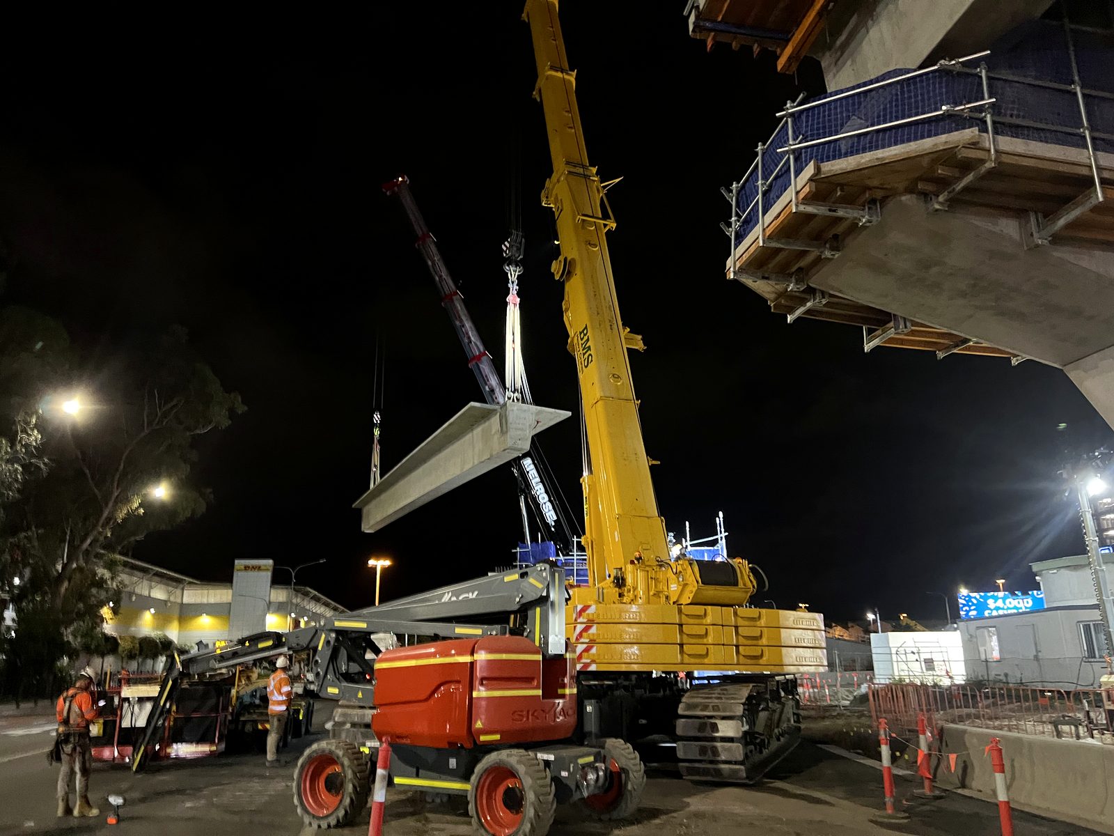 Crawler crane lifting a precast beam at night